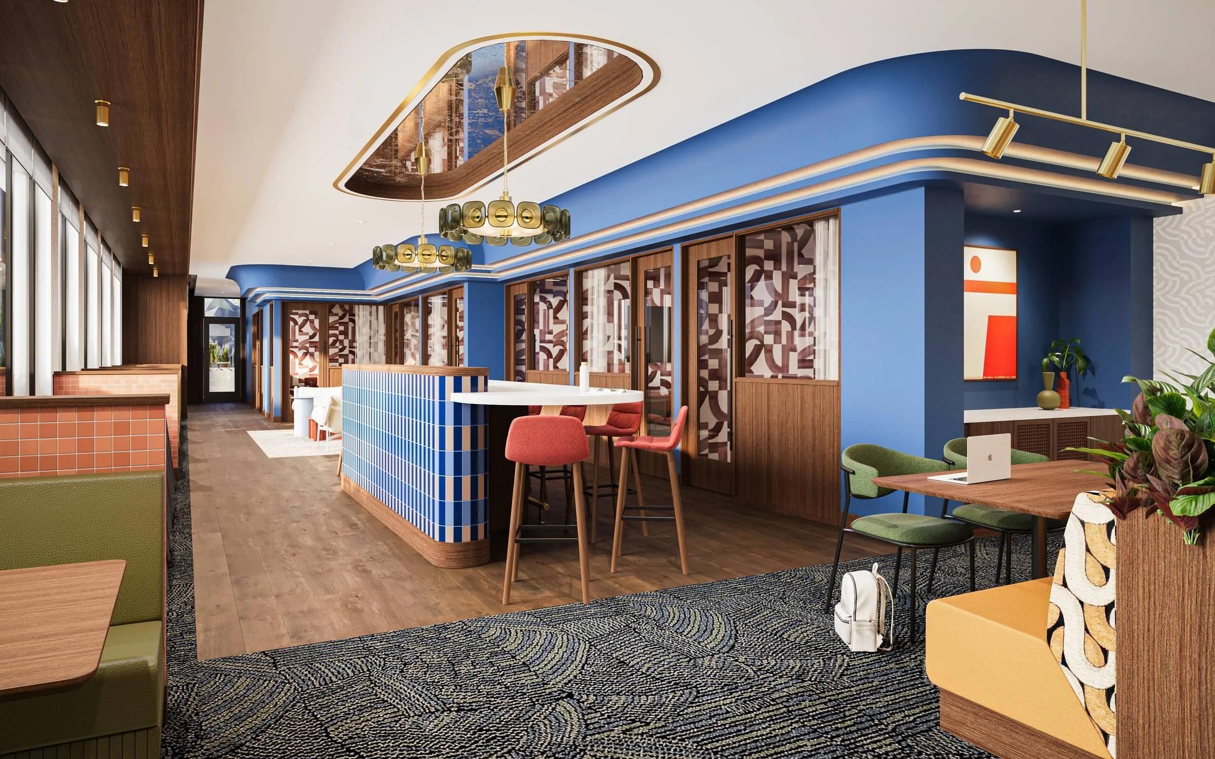 Modern coworking space with colorful decor, blue walls, patterned carpet, seating areas, and natural light.