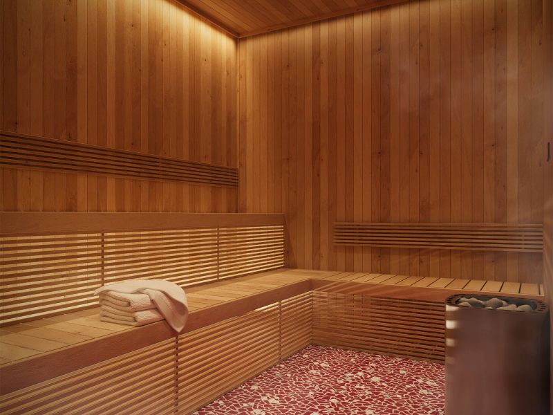 LOCAL On Delmar apartments Modern wooden sauna with stacked towels on a bench and a heater in the corner, red patterned floor tiles.