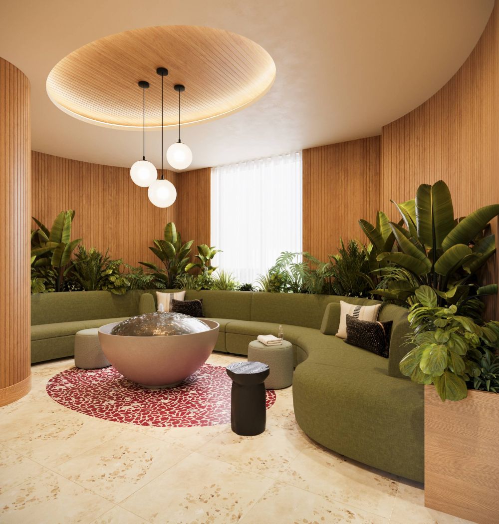 LOCAL On Delmar apartments Modern lounge with curved green sofa, round coffee table, indoor plants, and pendant lights on a red rug.
