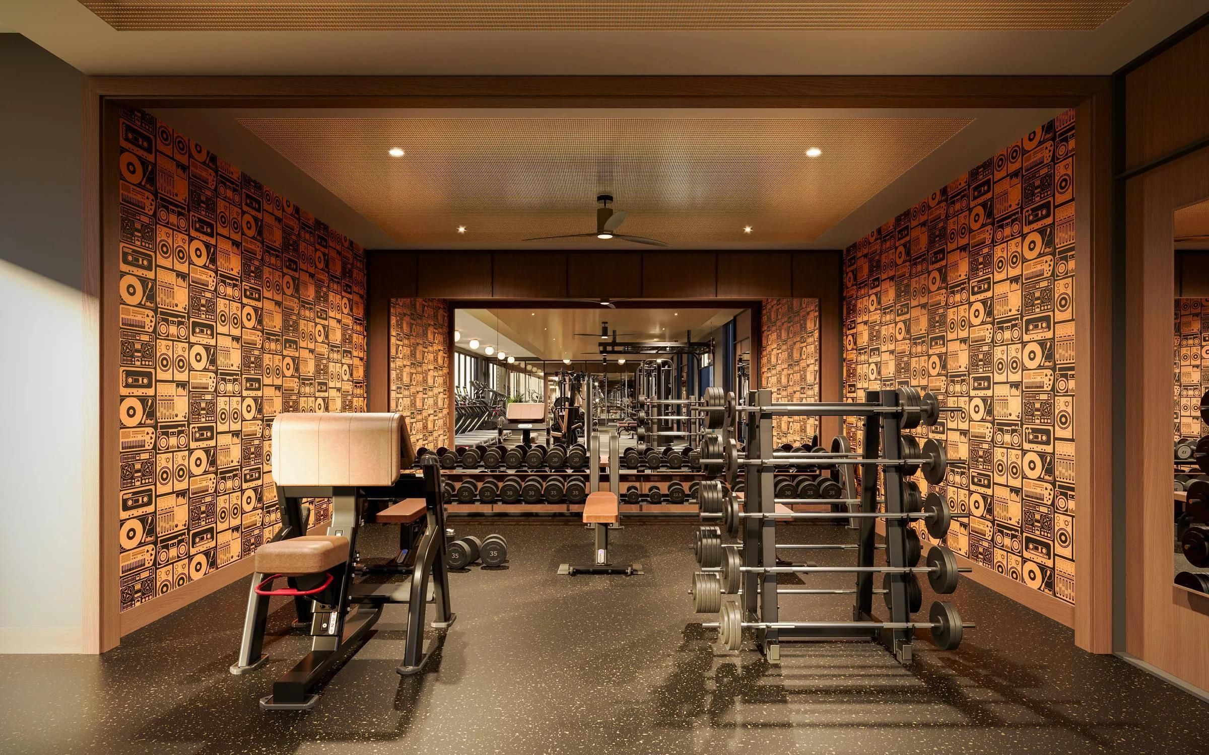 Modern gym with weight racks, benches, and large mirrors, featuring a wall with a retro speaker pattern.