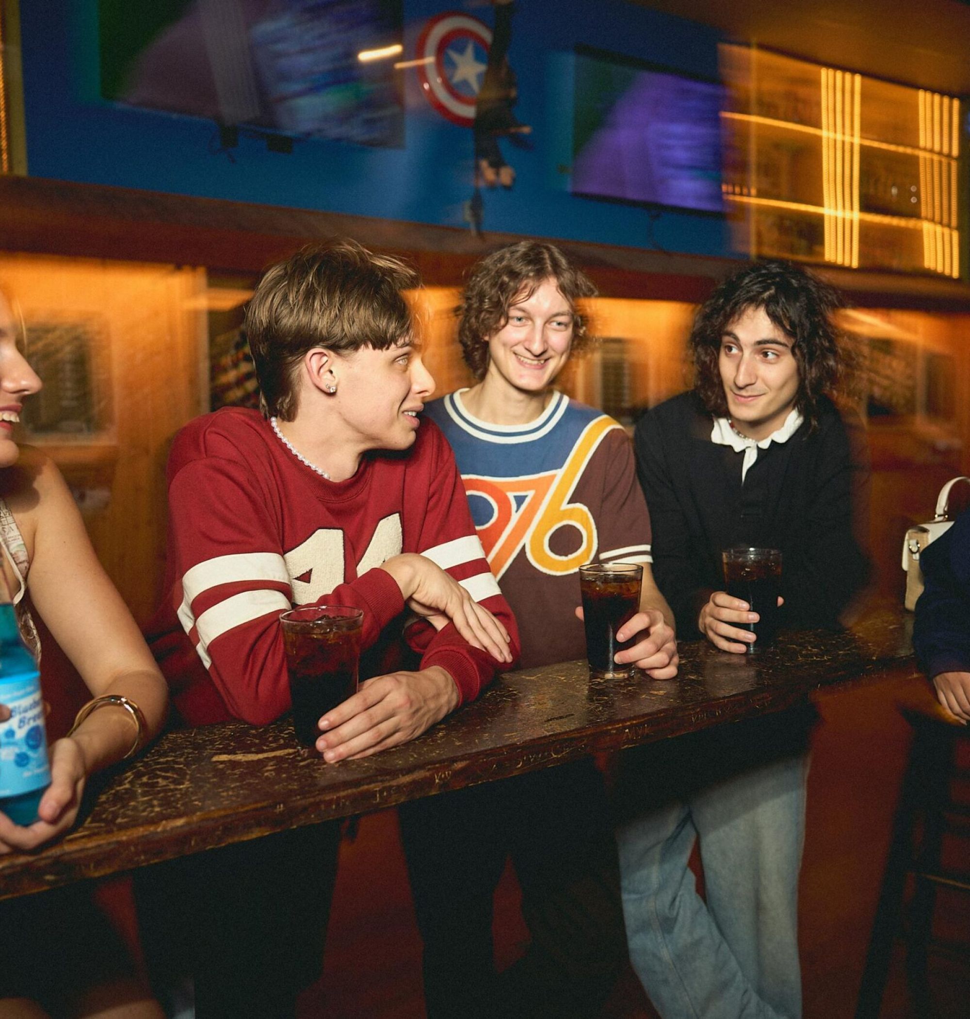 LOCAL On Delmar five young adults smile and chat at a bar, holding drinks and enjoying each other's company.