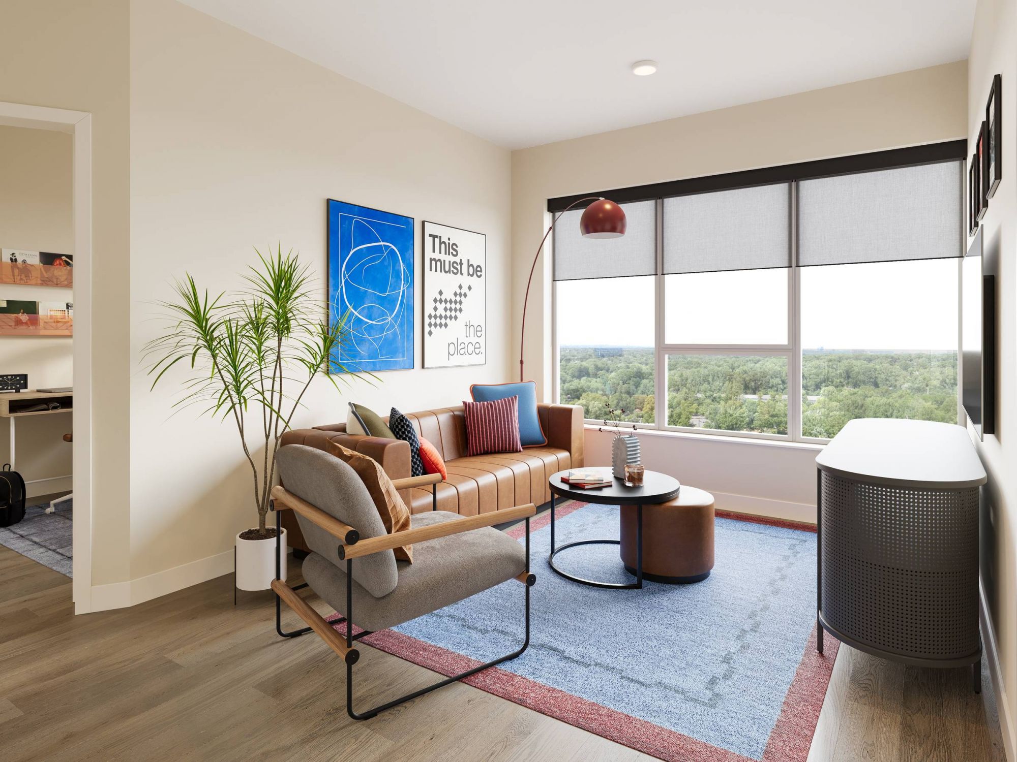 LOCAL On Delmar apartments Modern living room with a tan sofa, large window, blue rug, plants, and framed art on the walls.